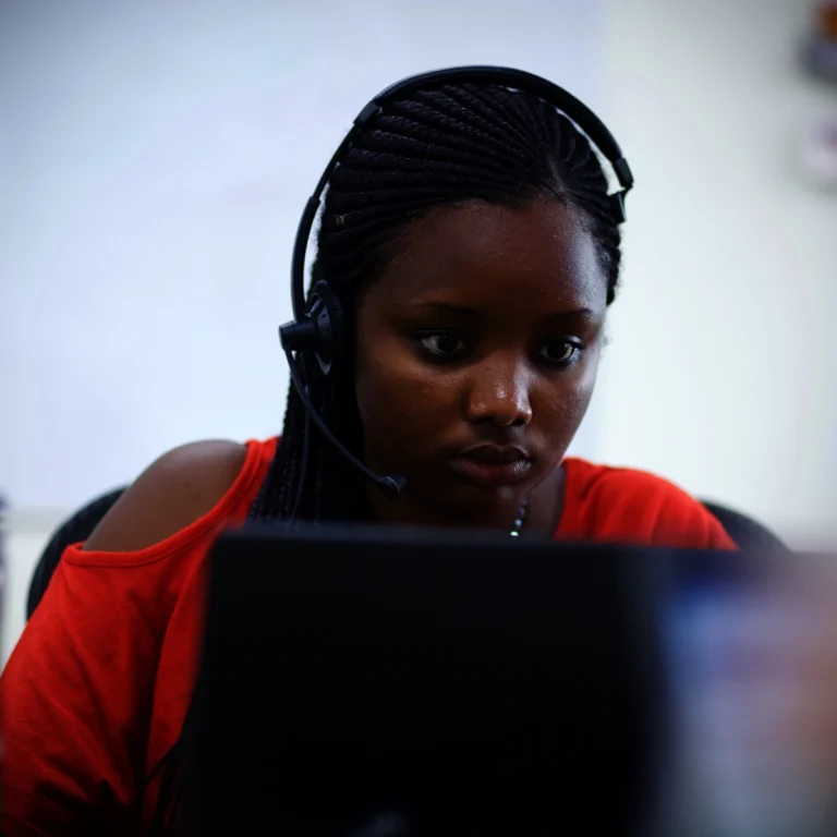 A young woman in a call centre in Africa working at her screen wearing a headset